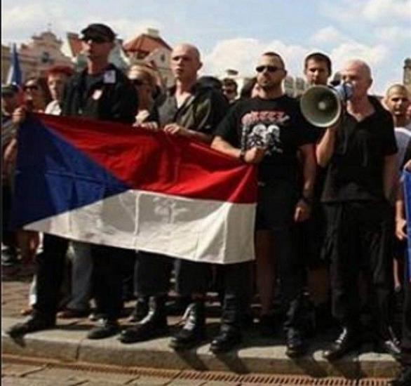 Ortel neváhá vyjít s ultrapravicovými extremisty do protiromského průvodu. Vlastenectví demonstruje naopak drženou vlajkou. Promo na vlastní kapelu má ale bezchybné.